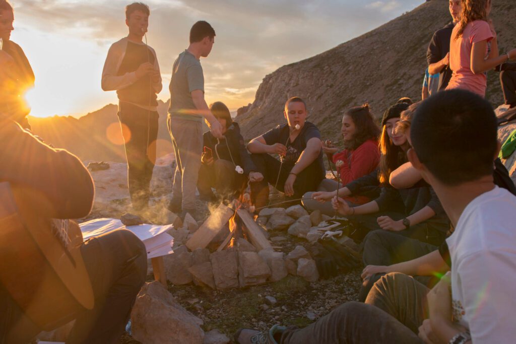 Group of students sitting around a campfire in the mountain