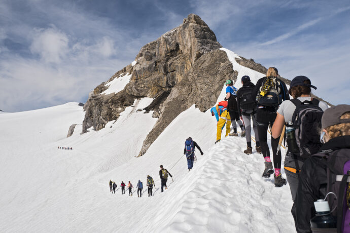 A group of people reaching to the top of a mountain