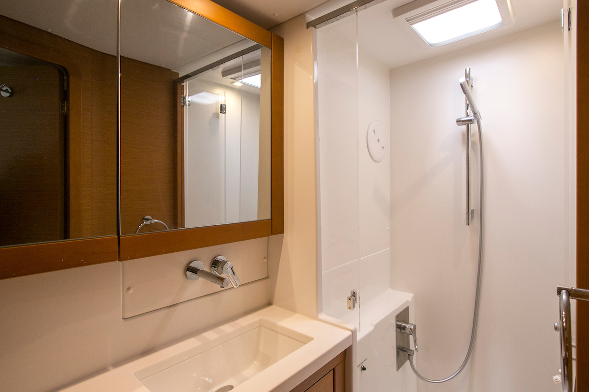 Compact yacht bathroom with vanity, mirrored cabinet, and walk-in shower under skylight