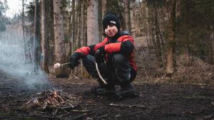 Student roasting a marshmallow over a small campfire at Winter camp
