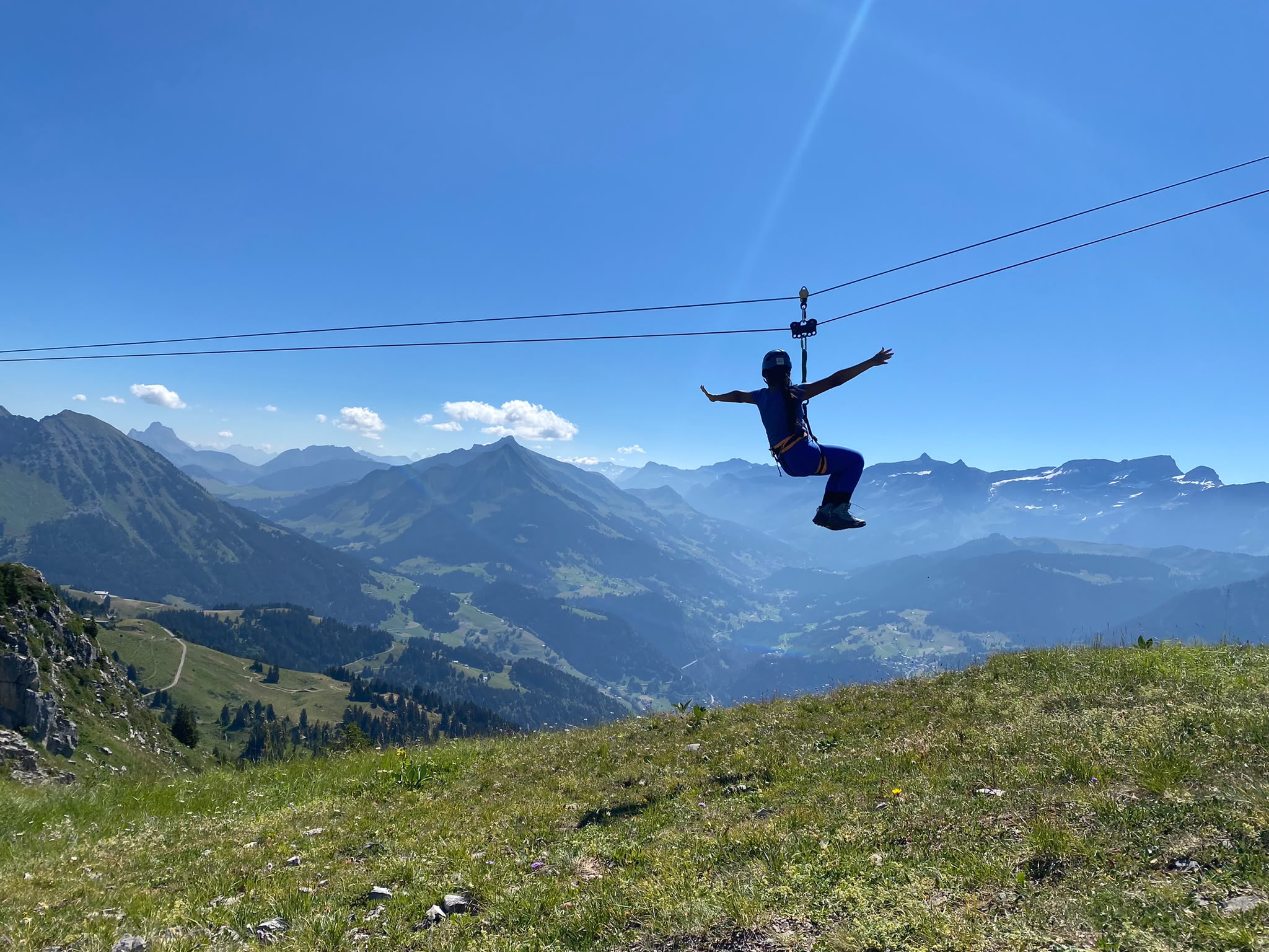 Zipline adventure over alpine mountains with panoramic views and clear blue sky.